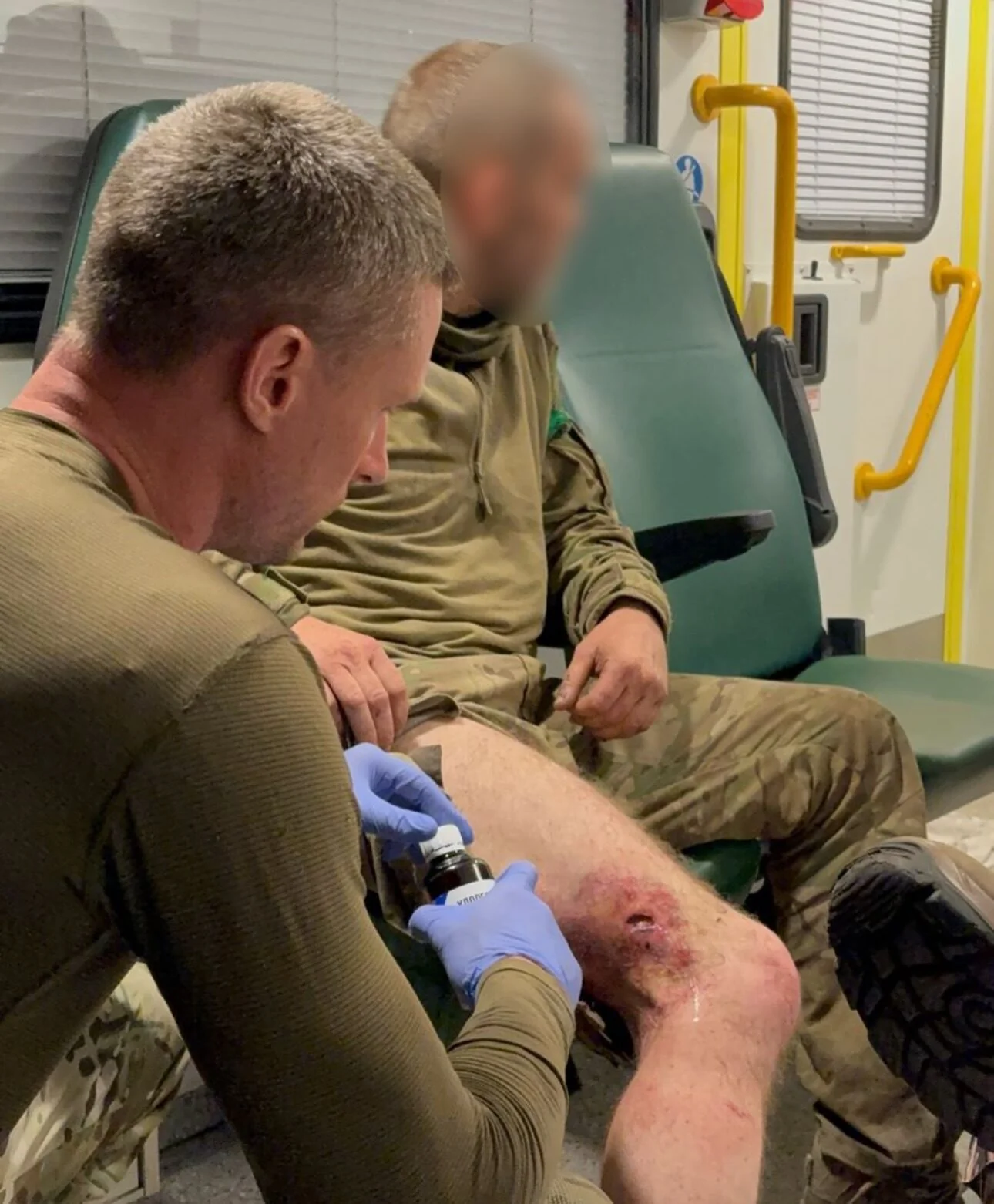 Медик обробляє глибоку рану на коліні військового в санітарному вагоні
