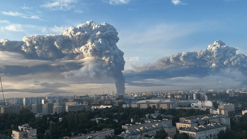Огромные столбы густого дыма над городской застройкой под голубым небом