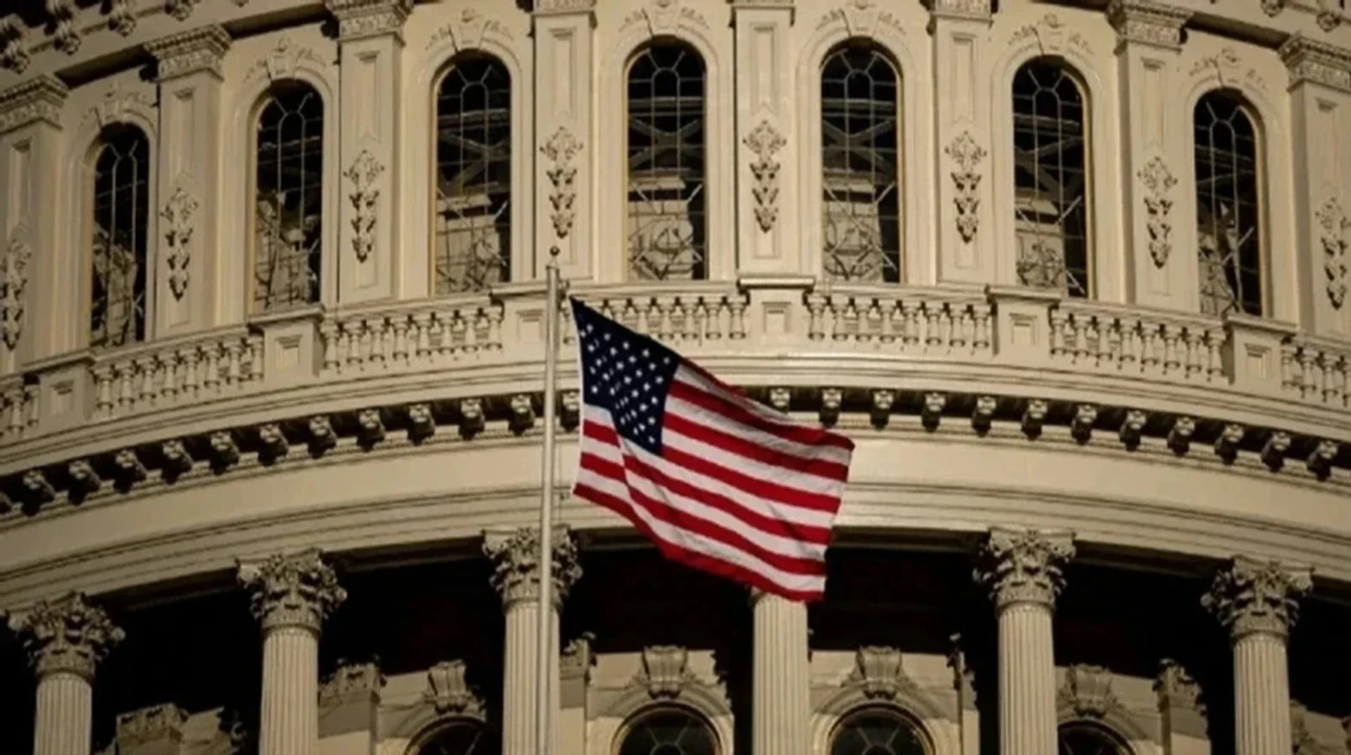 Капитолий США с американским флагом на фоне, где сенатор Линдси Грэм продвигает законопроект о санкциях против России