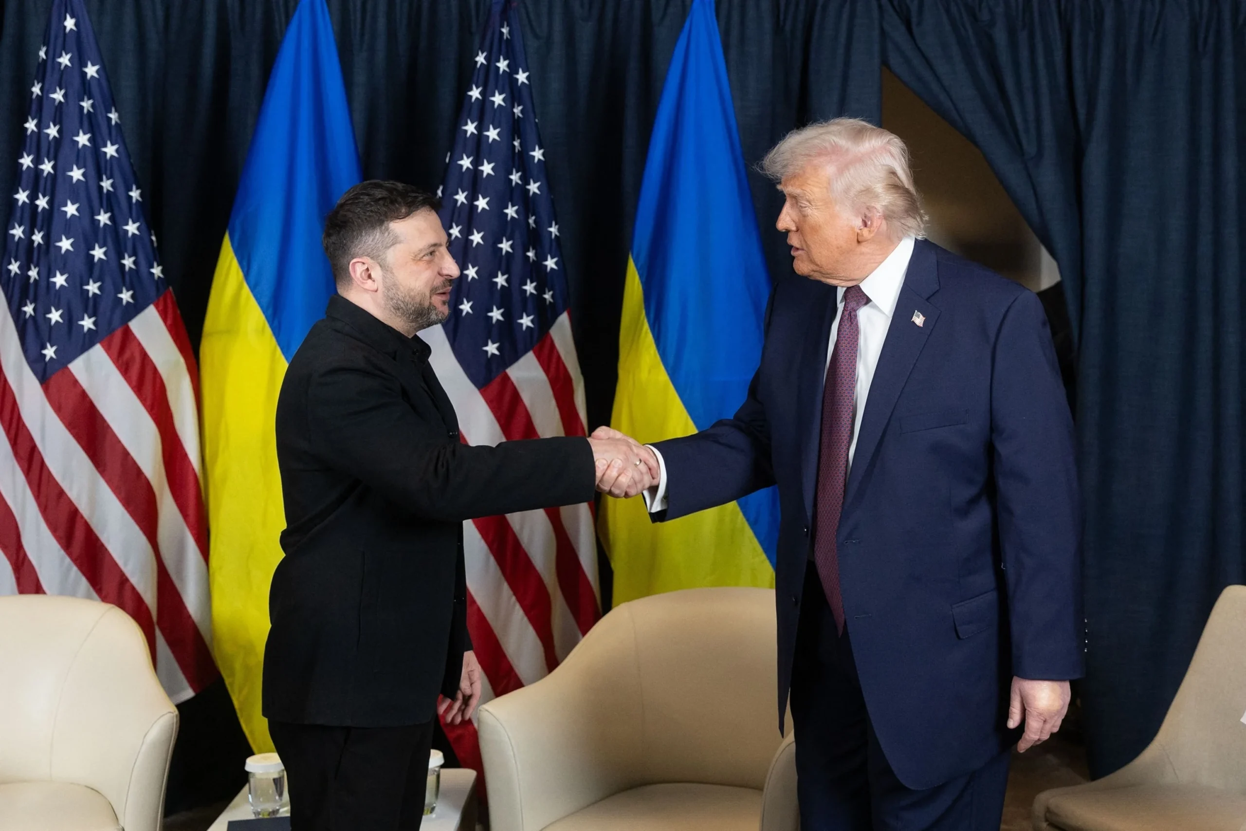 Зеленський і Трамп тиснуть руки на тлі прапорів США та України