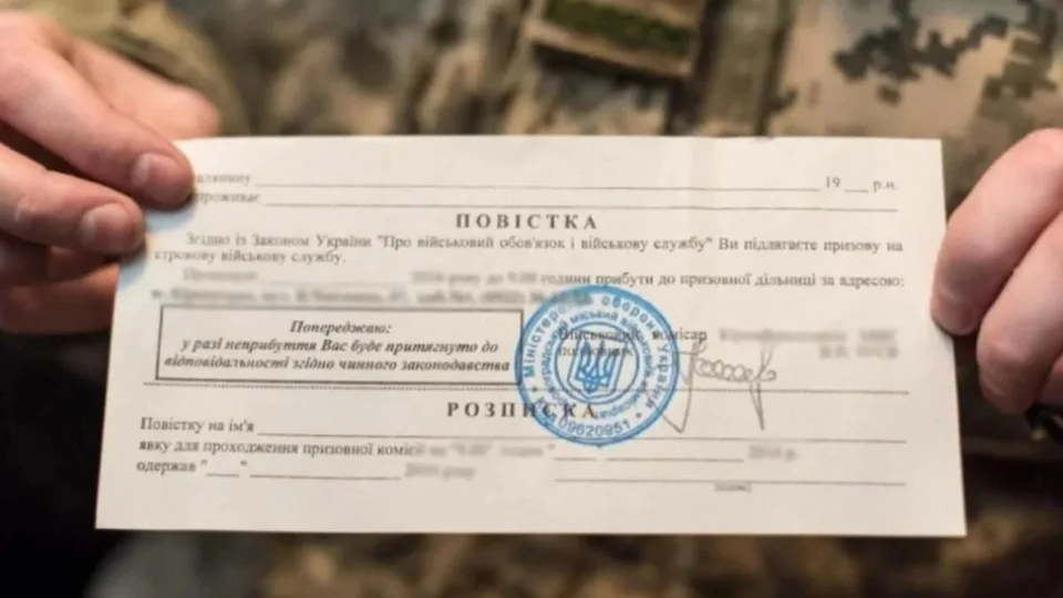 Руки в камуфляже держат официальную повестку из военкомата со штампом