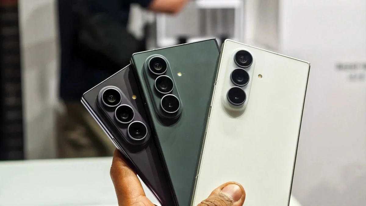 Три складані смартфони Galaxy Fold у фіолетовому зеленому та білому кольорах у руці