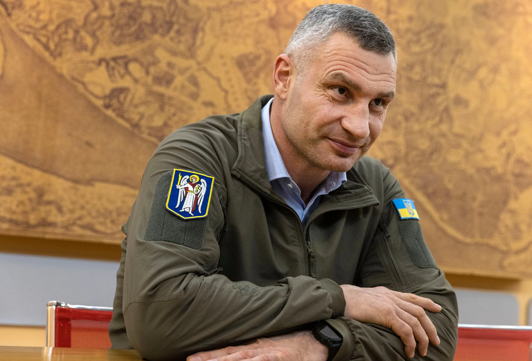 Віталій Кличко в оливковій куртці з нашивками сидить за столом, схрестивши руки