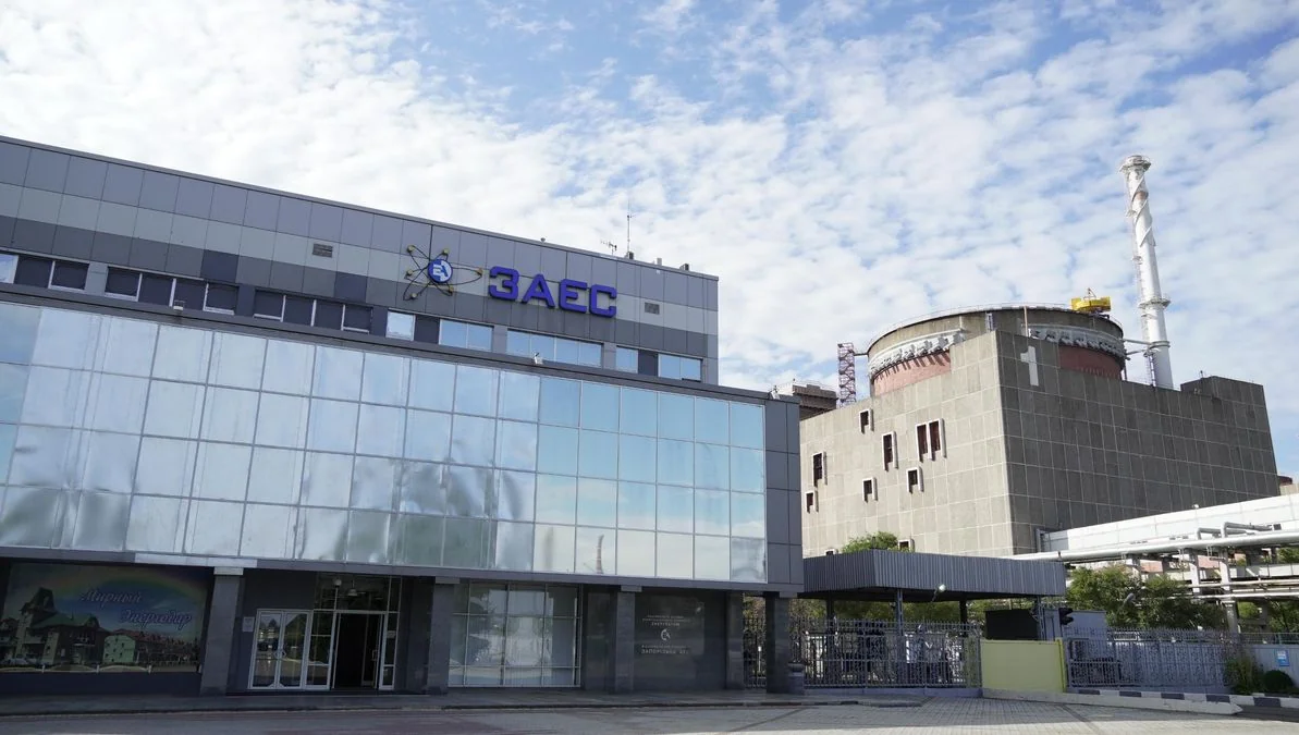 Адміністративна будівля ЗАЕС з логотипом та реакторний блок на задньому плані
