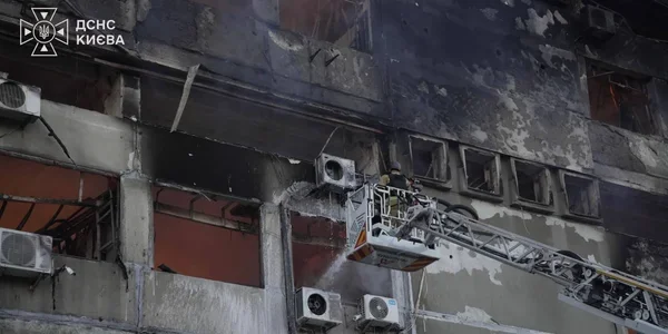 Рятувальники на автодрабині гасять пожежу на фасаді пошкодженої будівлі