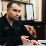 Кирило Буданов у чорній формі Офісу Президента за столом з документами