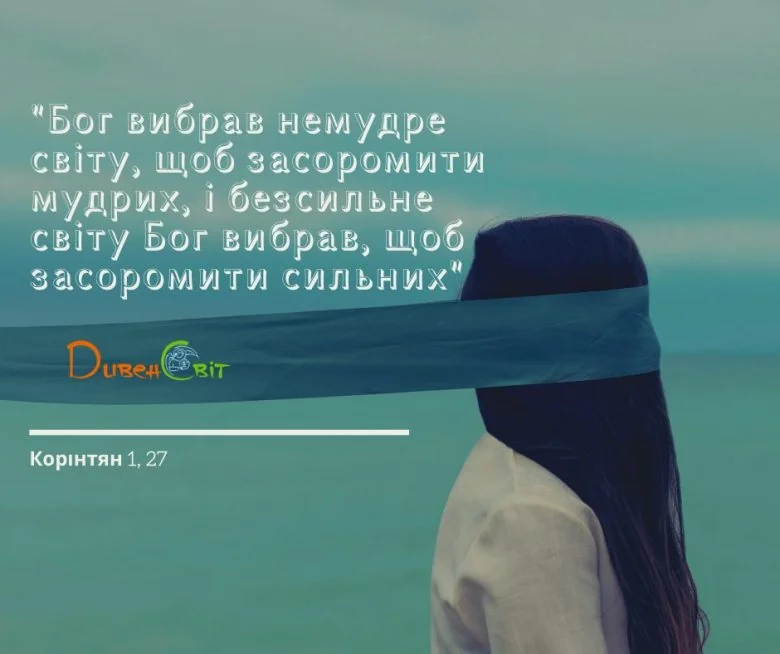 Жінка з довгим волоссям і пов’язкою на очах стоїть спиною на тлі моря