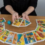Жінка тримає три карти таро над розкладом півколом на столі